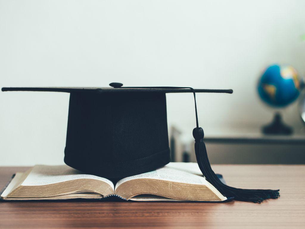 Imatge de recurs. Llibres i un barret de graduat