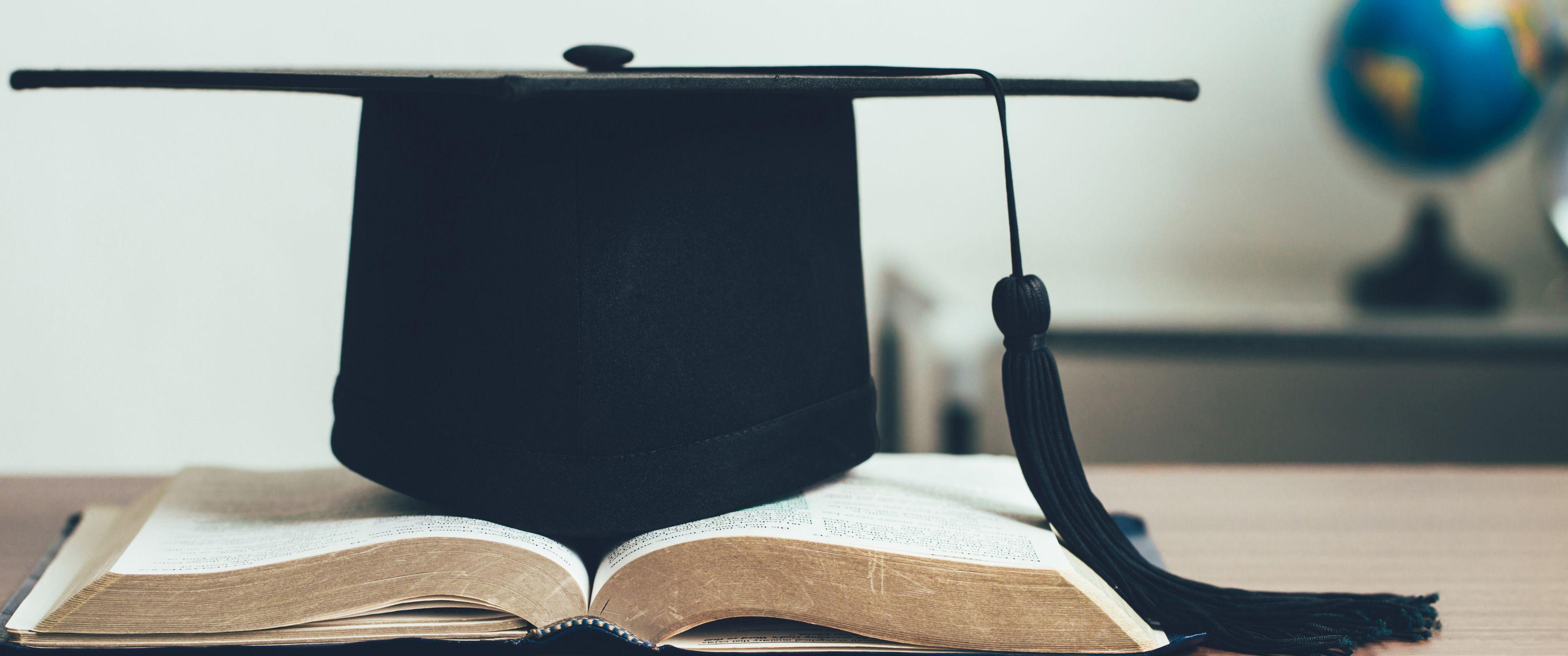 Imatge de recurs. Llibres i un barret de graduat