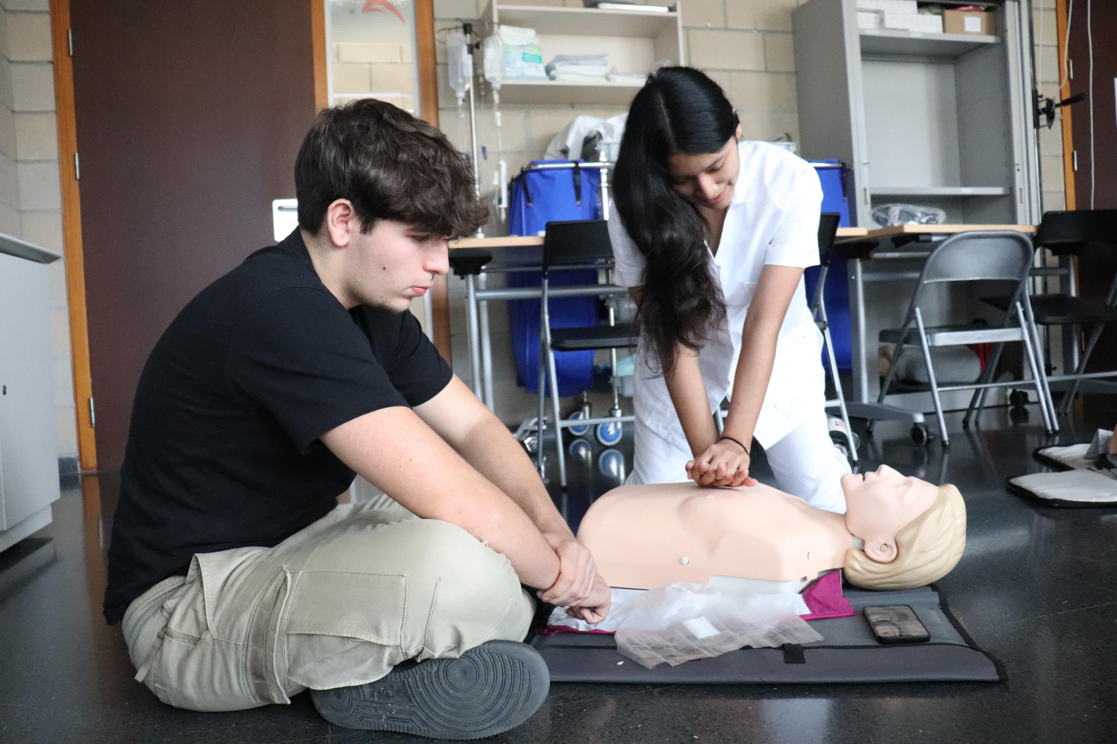Dos estudiant d'infermeria practicant fer CPR a un maniquí