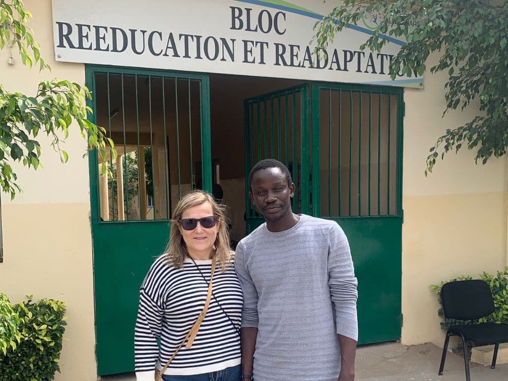 La professora Carme Vaca a la porta de l'escola on van anar, amb un dels participants