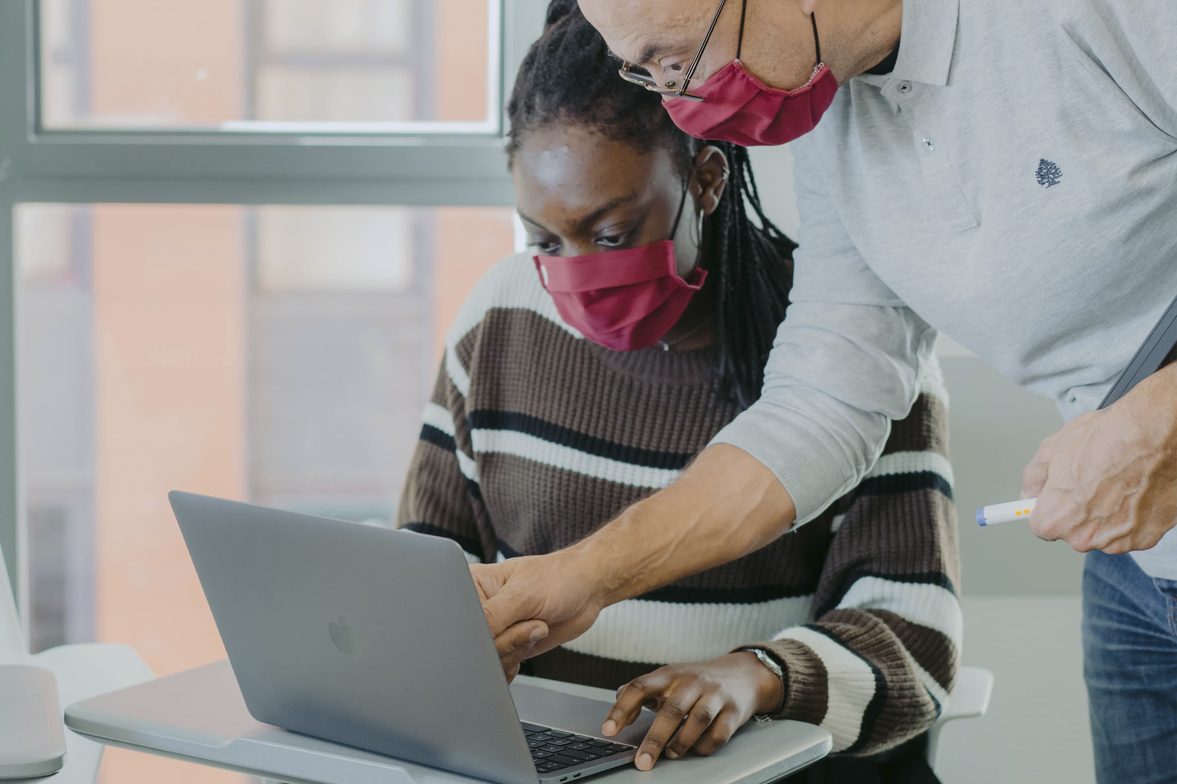 Alumne i professor parlant mirant el portàtil